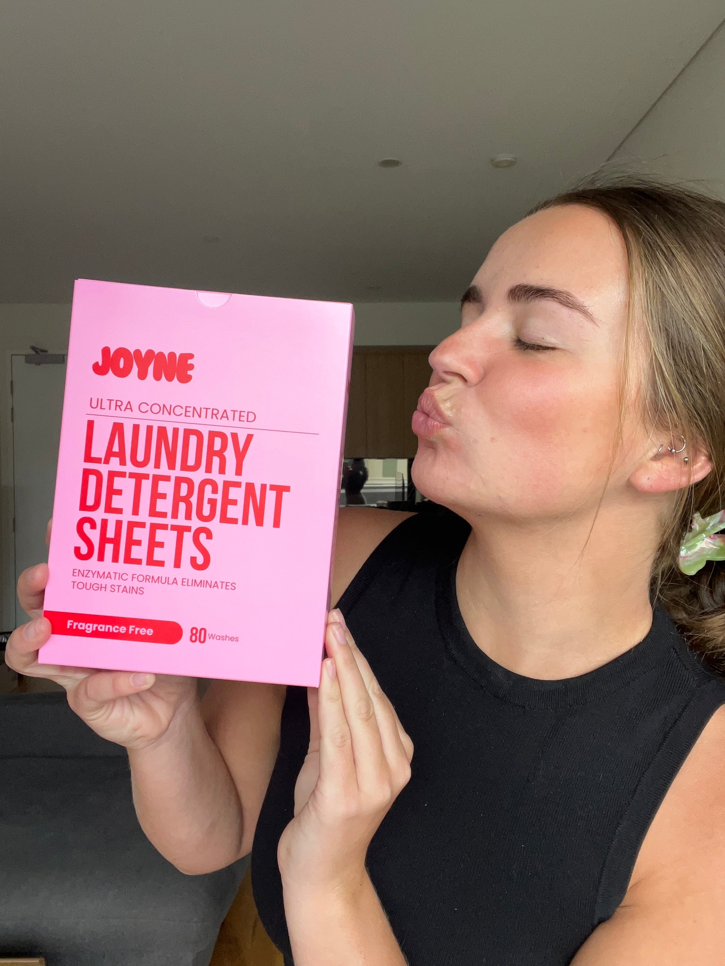 A women kissing a pink box of laundry detergent sheets